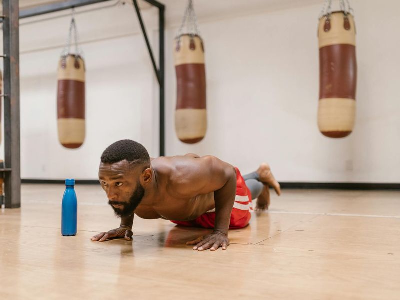 A focused man doing a push-up in a modern, dark-themed gym.