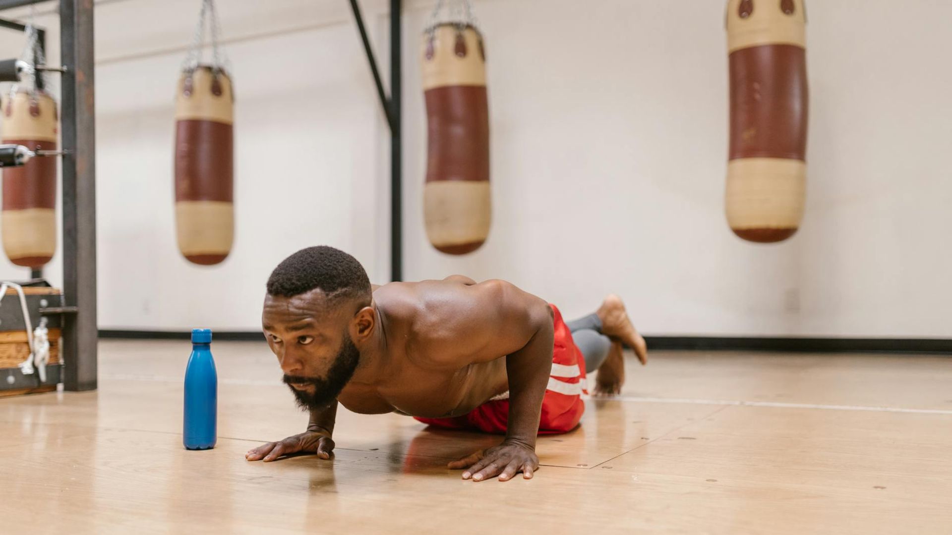 A man performing a focused bodyweight exercise in a minimalist gym.